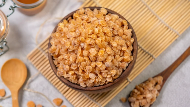 Cone Crackels 3 A wooden bowl filled with Cone Crackles, flat caramelised nut pieces used as toppings for ice cream and premium desserts.