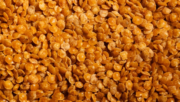 Cone Crackles 2 A wooden bowl filled with Cone Crackles, flat caramelised nut pieces used as toppings for ice cream and premium desserts.