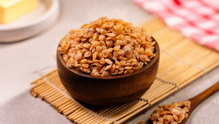 Cone Crakles 1 A wooden bowl filled with Cone Crackles, flat caramelised nut pieces used as toppings for ice cream and premium desserts.