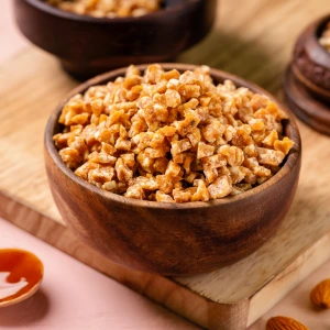 A wooden bowl filled with nutty Sprinkles, crunchy pieces used as toppings for ice cream and premium desserts.